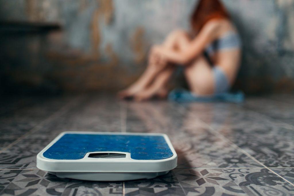 Anorexic woman sitting on the floor, weight loss