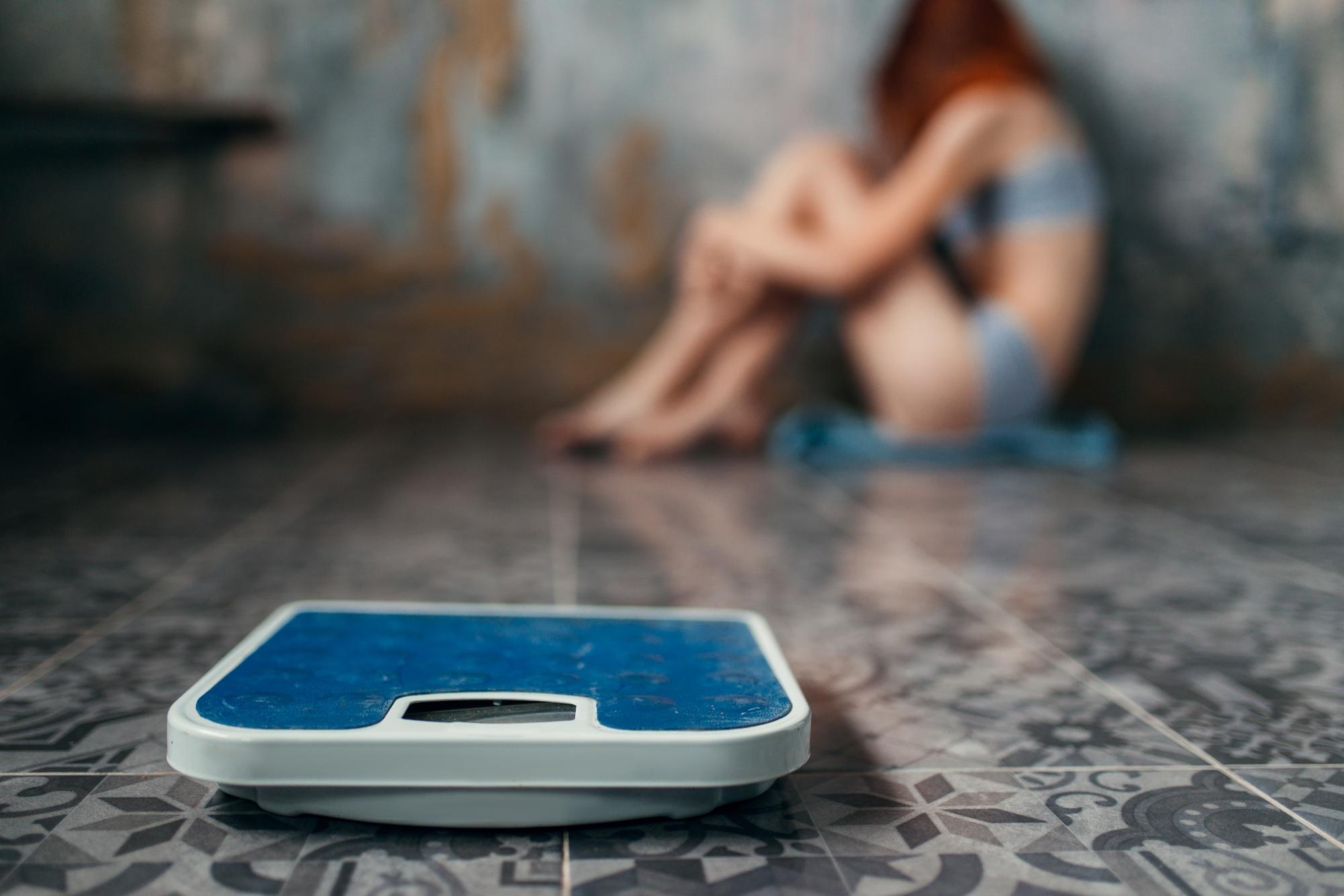 Anorexic woman sitting on the floor, weight loss