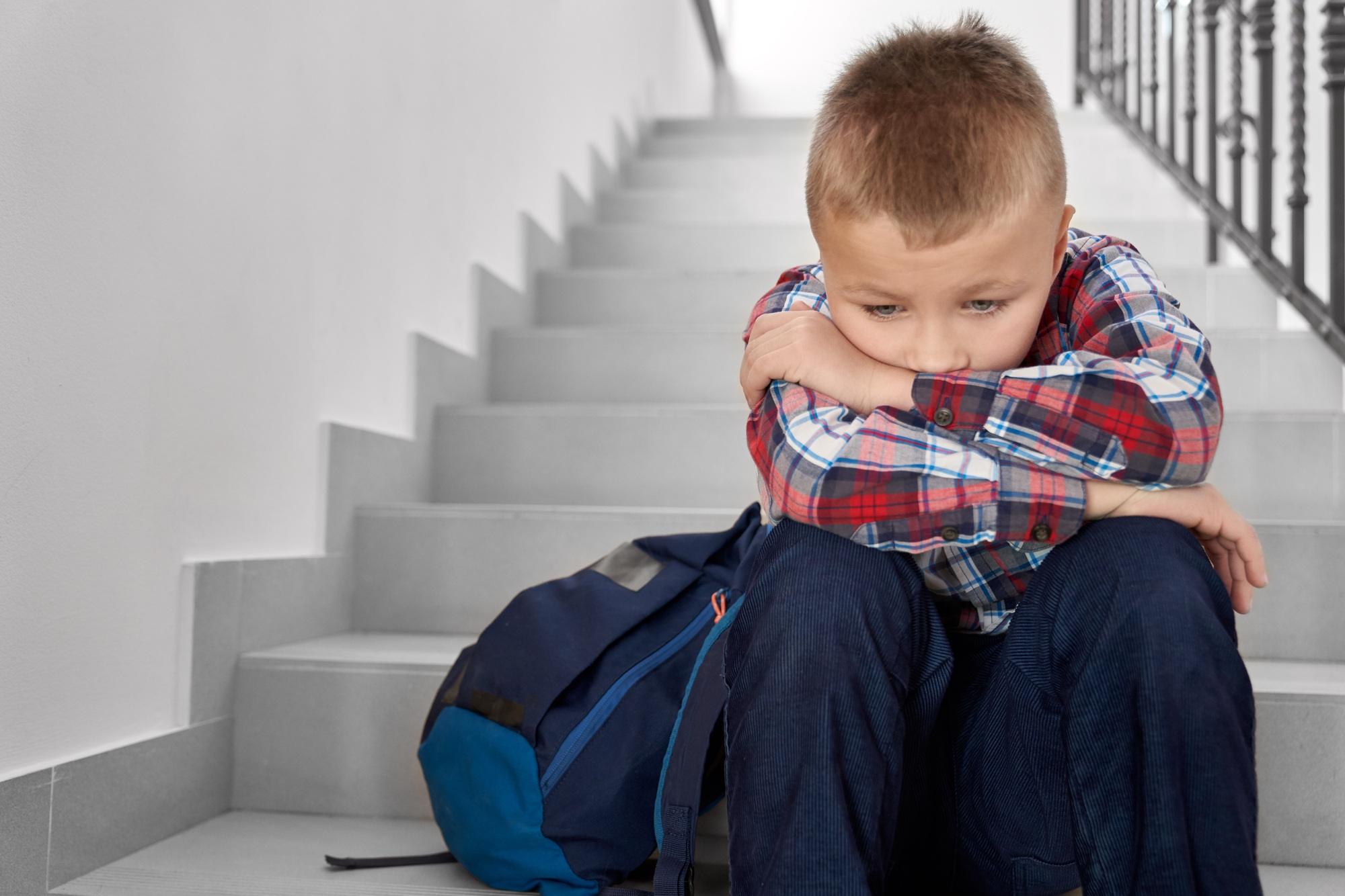 Sad boy of primary school sitting on stairwell