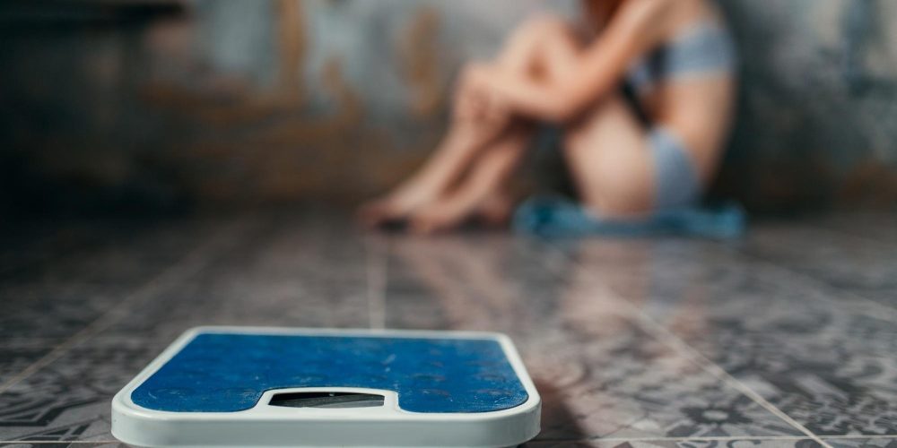 Anorexic woman sitting on the floor, weight loss