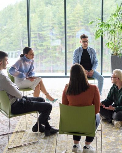 Corporate business team meeting with a manager or coach. Group of happy diverse, multiracial people sitting in a circle