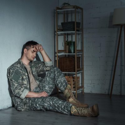 Frustrated military man with ptsd sitting on floor after homecoming