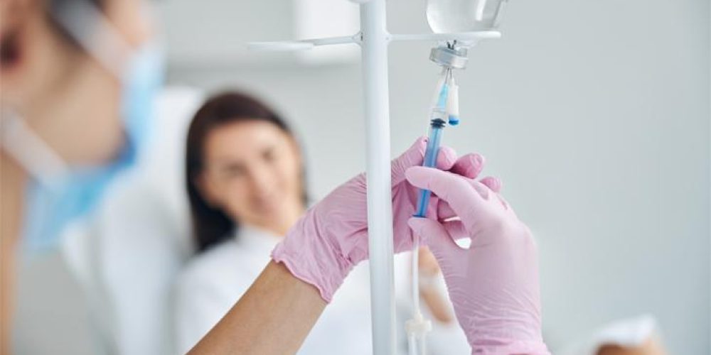 Experienced Caucasian heath care worker preparing a dark-haired female patient for the intravenous vitamin therapy