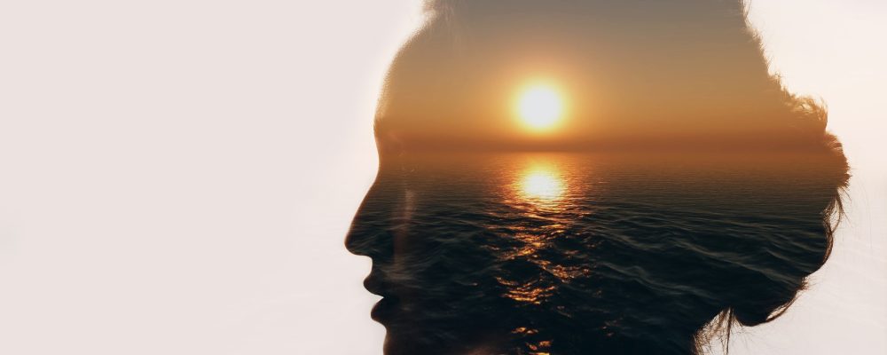 Multiple exposure sunrise and sea inside woman silhouette. Psychology concept