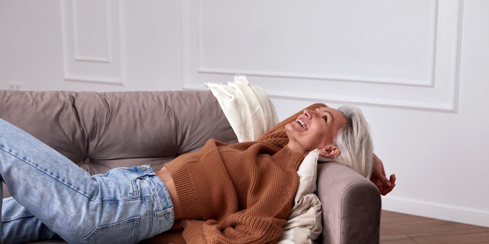 Positive middle aged woman laughing on couch