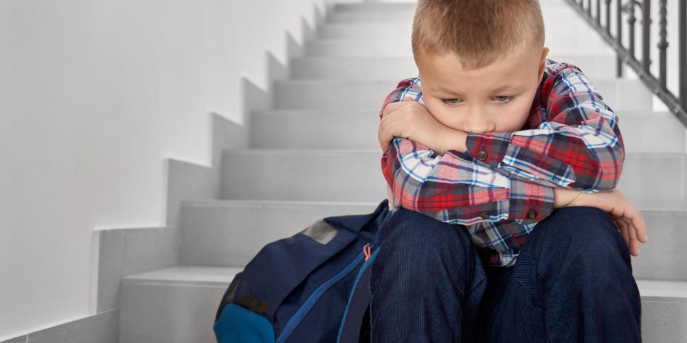 Sad boy of primary school sitting on stairwell
