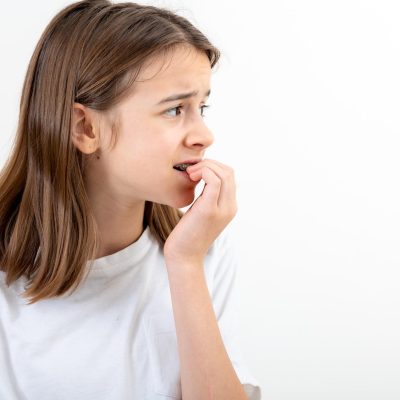 Scared and anxious girl, biting her fingernails on a white background isolated.