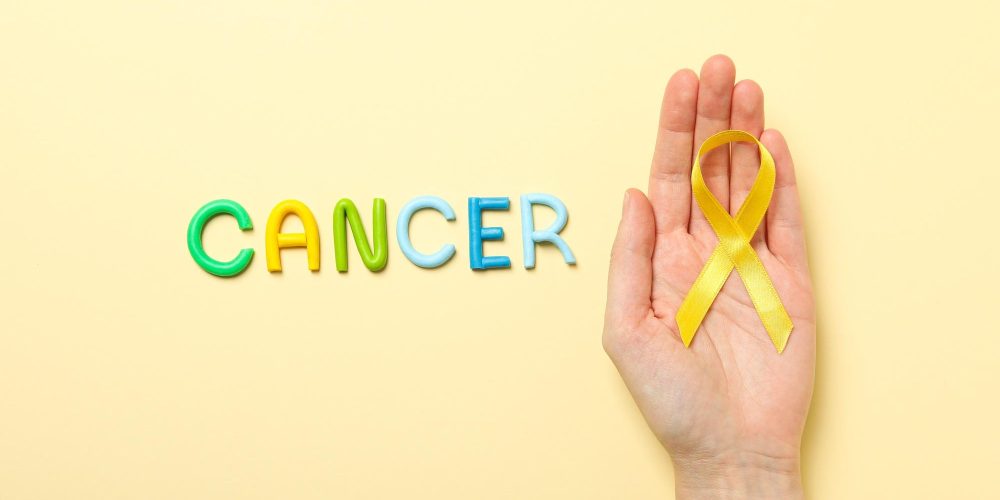 The inscription Cancer in colorful letters with a yellow ribbon